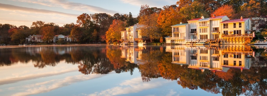 Lakefront town homes catch the first light of morning and reflect into a calm Lake Anne in Reston, Virginia.
